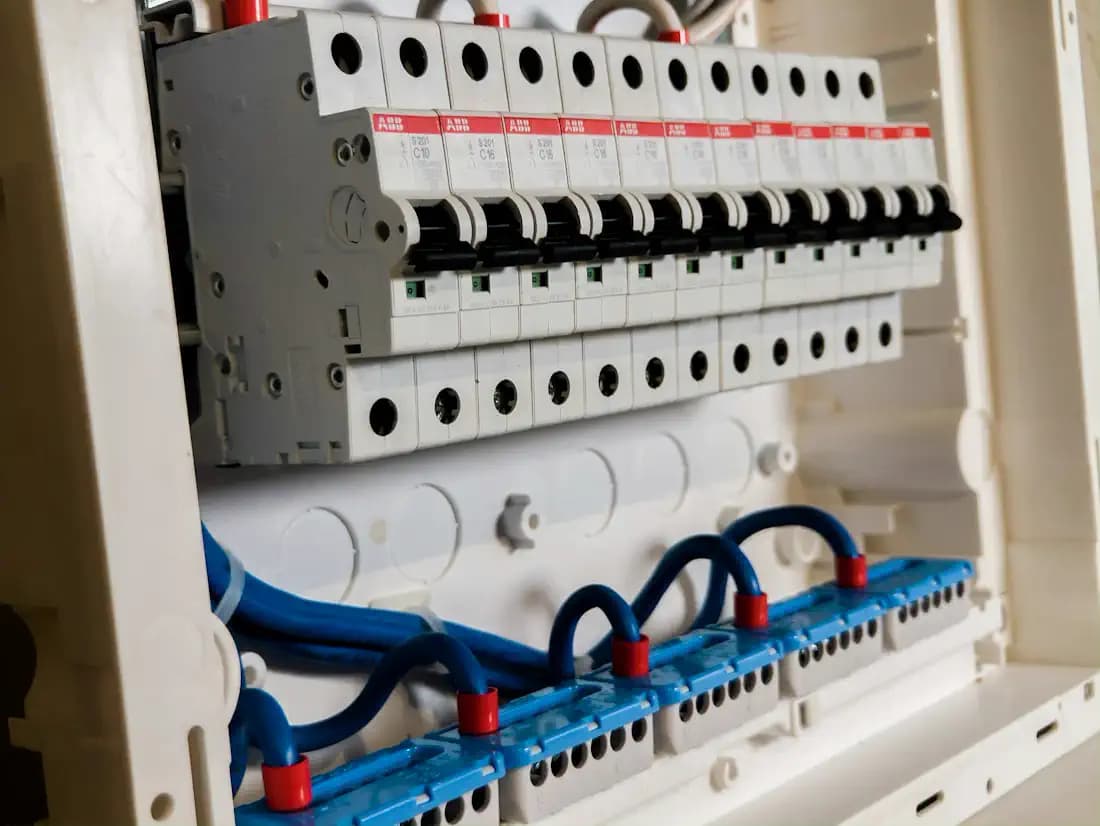Disjuntores brancos num quadro de luz, com fios azuis