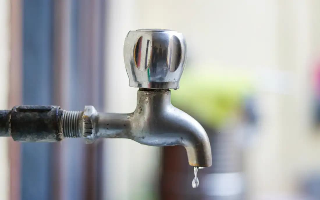 Torneira de metal com uma gota de água caindo